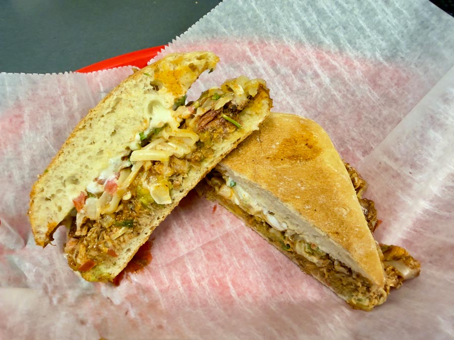 Two halves of a toasted sandwich from Fat Daddy's Menu with melted cheese and shredded meat.