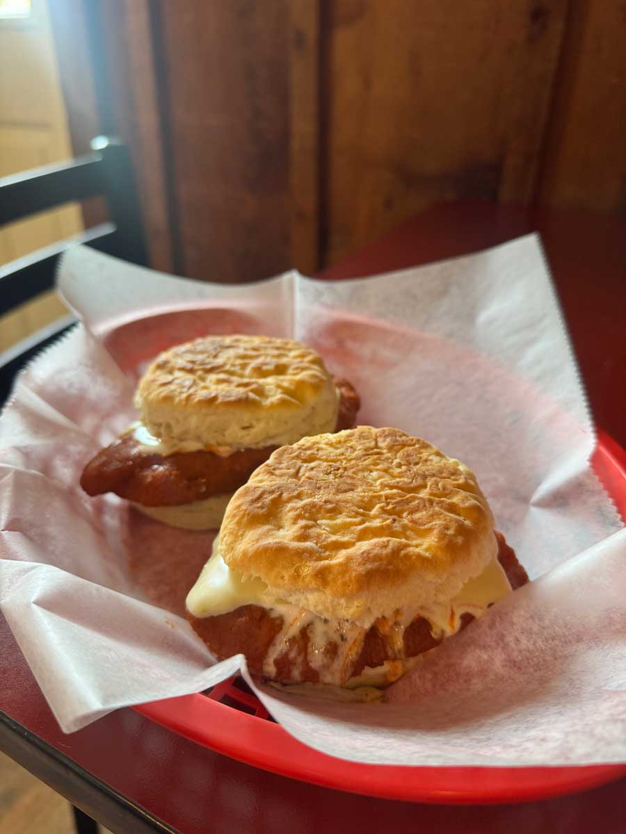 Two chicken and cheese biscuit sandwiches from Fat Daddy’s Menu in a red basket on a table.